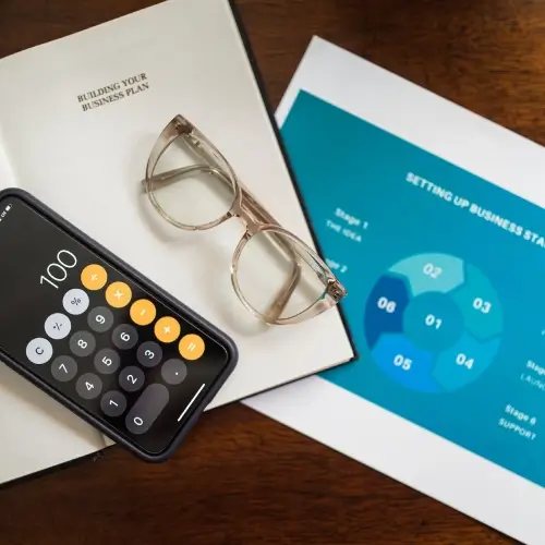 Calculadora, libro, papeles de presentación y lentes