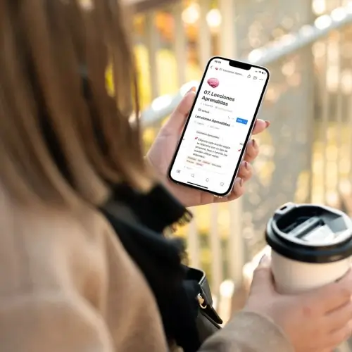 Chica usando su celular mientras toma café