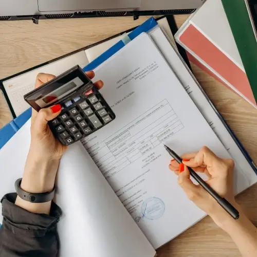 Manos sosteniendo una calculadora y papeles