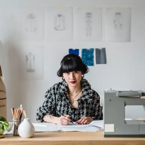 Mujer sentada detrás de una mesa con una máquina de coser