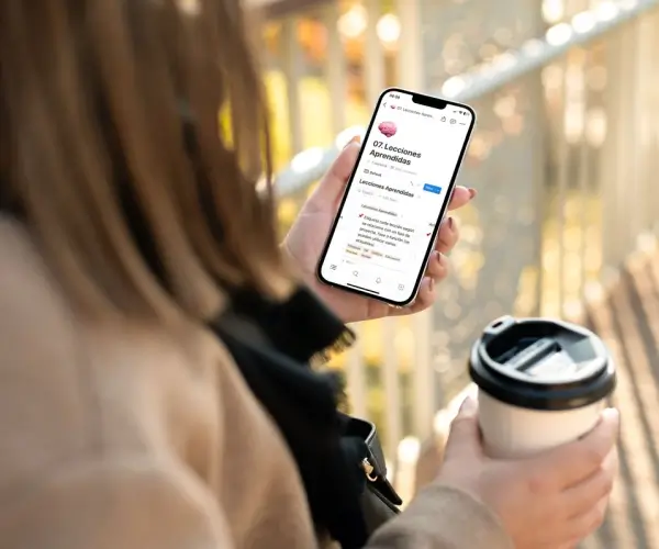 Chica usando su celular mientras toma café