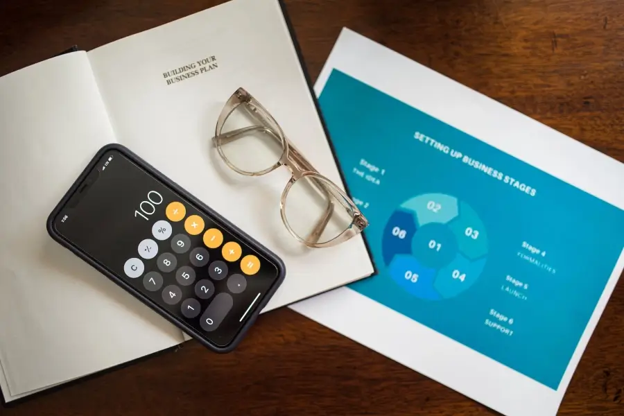 Calculadora, libro, papeles de presentación y lentes