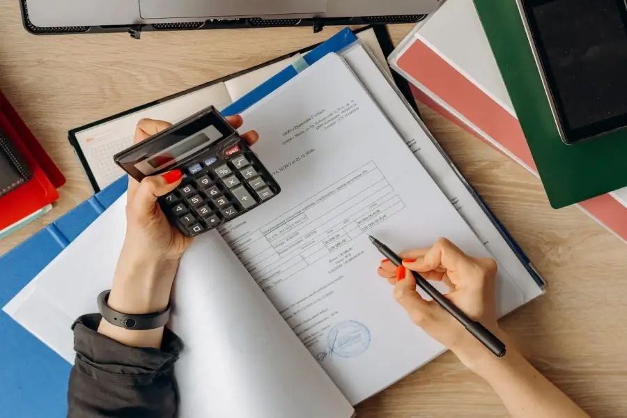 Manos sosteniendo una calculadora y papeles