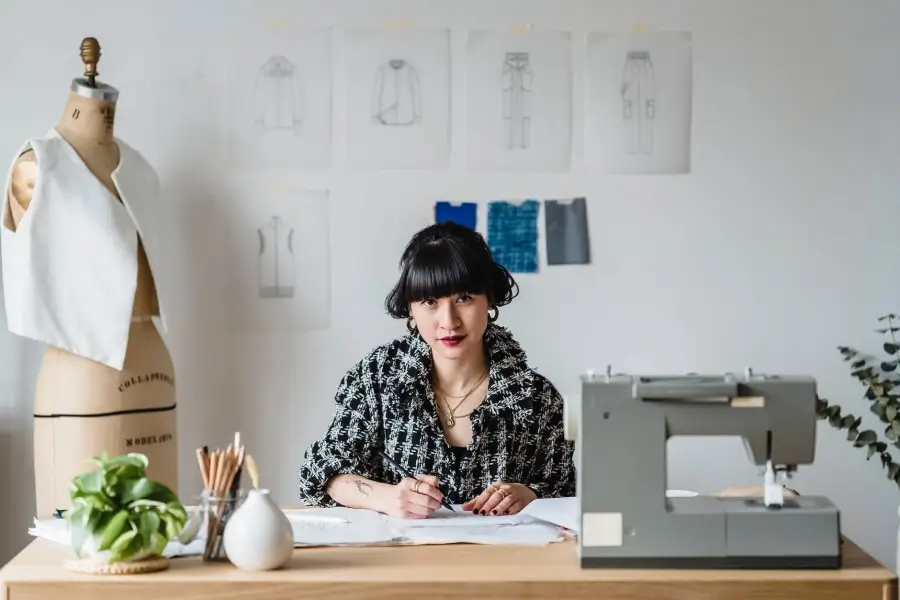 Mujer sentada detrás de una mesa con una máquina de coser